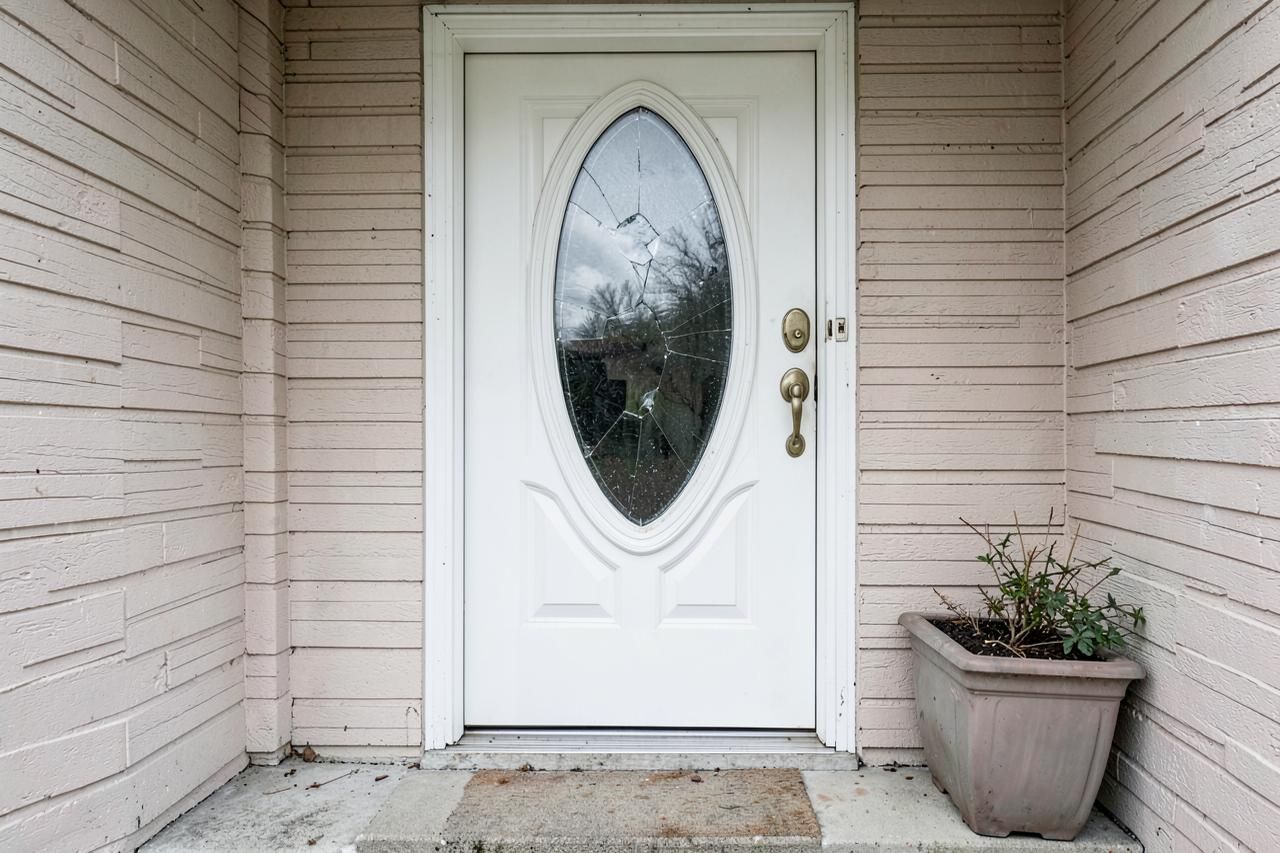 White front door with a cracked oval glass insert before replacement